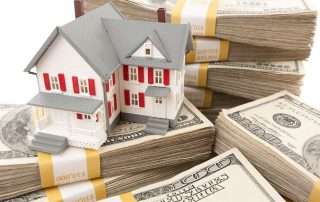 Model home sitting on a stack of 100 dollar bills