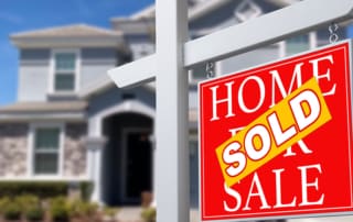 Real estate sold sign in front of large home