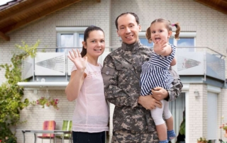 Military man with family standing in front of new home