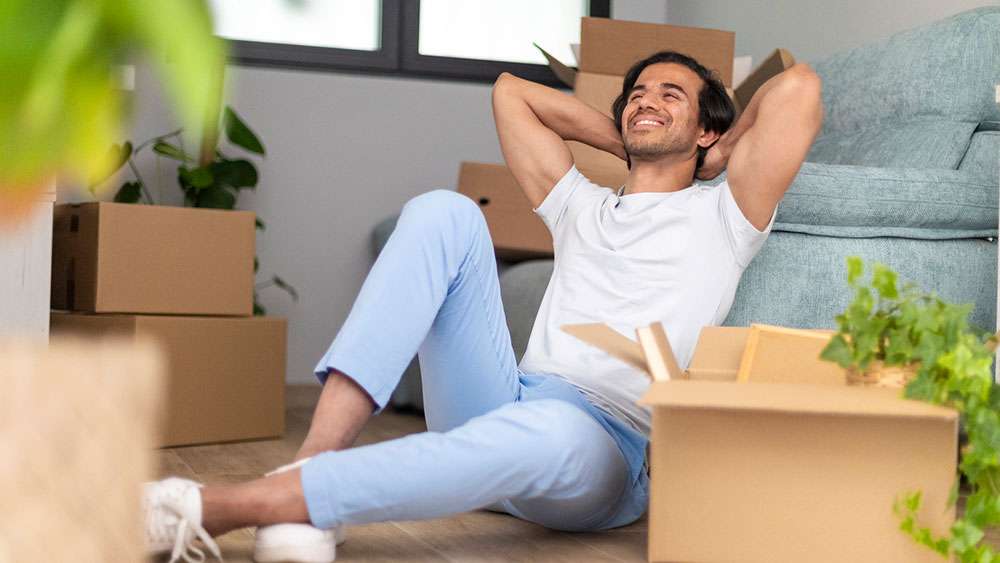 Real Estate for Singles: A Guide to Solo Homeownership Young man takes a break from moving into his new home