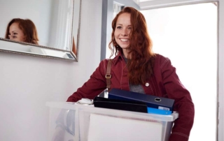 Female College Student Carrying Box Moving Into Accommodation