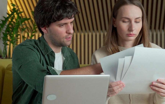 Serious young couple considering buying a home, going over facts and listings.