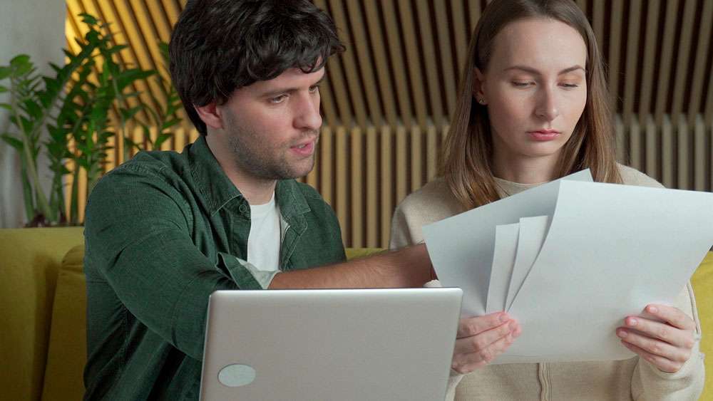 The Psychology of Home Buying: Understanding Your Emotional Connection Serious young couple considering buying a home, going over facts and listings.