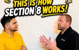Two men discuss in front of a wall sign that reads 'NO MAN, THIS IS HOW SECTION 8 WORKS!'