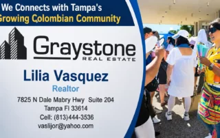 Signboard for Graystone Real Estate featuring Lilia Vasquez, Realtor, with contact details; people gathering at an outdoor event nearby.